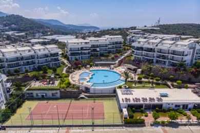 Lichte Alanya appartement woonkamer met witte tegelvloeren, een moderne keuken en toegang tot een balkon, wat een verfrissende sfeer creëert.