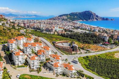 Björt stofa í Alanya íbúð með bleikum sófum, opnu eldhúsi og aðgangi að svölum með fallegu útsýni.