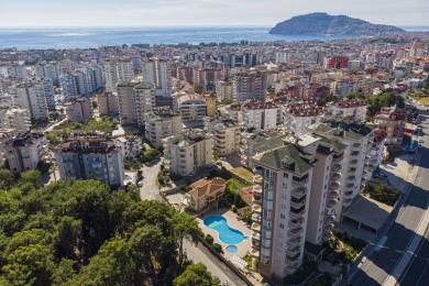 De heldere woonkamer in Alanya is voorzien van marmeren vloeren, grote ramen, een eethoek en comfortabele zitplaatsen met kleurrijke kunstwerken.