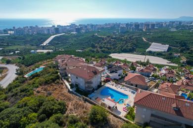 Alanya eiendom stue med sorte skinnsofaer, et kaffebord i tre og lyse fliser.