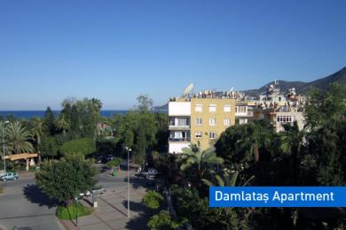 Bright Alanya living room features comfortable armchairs and a panoramic window view of the mountains.
