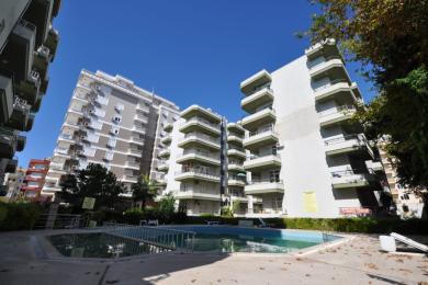 Alanya woning balkon uitzicht op een aangelegde binnenplaats en nabijgelegen appartementencomplexen op een zonnige dag.