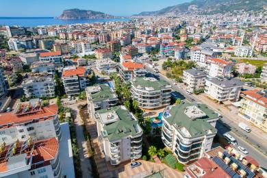 Rymlig balkong i Alanya med vitt bord, stolar och naturskön bergsutsikt.