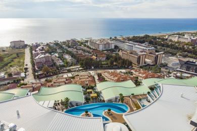 Propriedade em Alanya: Elegante área de estar e jantar com pisos de mármore, móveis brancos e um lustre impressionante.
