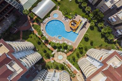 Alanya-Immobilienbalkon mit Glasgeländern, Korbmöbeln und Panoramablick auf Stadt und Berge.