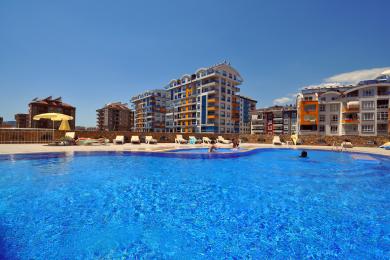 Alanya mulkidagi oshxona, oq shkaflar, zanglamaydigan po'latdan yasalgan muzlatgich, kafel qoplamasi va yorug', havodor muhitga ega.
