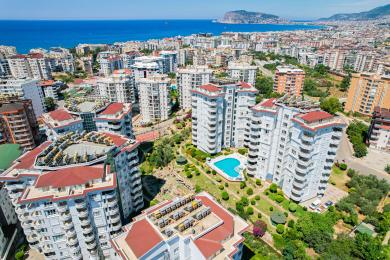 فضای نشیمن روشن و با طرح باز در آلانیا دارای کف مرمر، آشپزخانه مدرن و صندلی های راحت زیر لوستر است.