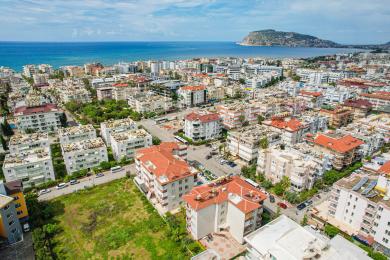 Living spațios în Alanya cu podele de marmură, scară din lemn, scaune confortabile și lumină naturală de la ușile balconului.