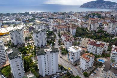 Alanya mulkidagi ochiq oshxonasi, jigarrang divanlari va yorqin, jozibali muhiti bilan yashash xonasi.