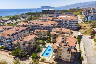 Alanya Immobilie Wohnzimmer mit beigen Sofas, hellem Licht, Jalousien und einer entspannten, komfortablen Atmosphäre.