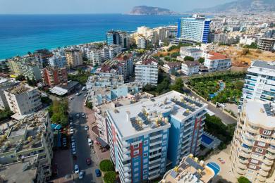 Soggiorno di una proprietà ad Alanya con pavimenti in marmo, divani in pelle bianca e accesso al balcone luminoso e arioso.