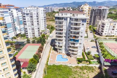 Alanya'da ahşap masa ve sandalyeli, mermer zeminli, parlak güneş ışığı alan ve şehir manzaralı balkon.