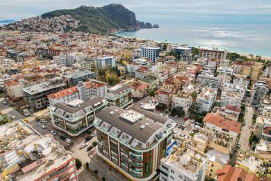 Alanya ingatlan légifelvétele, amely modern apartmanházakat mutat a strand és a város közelében.