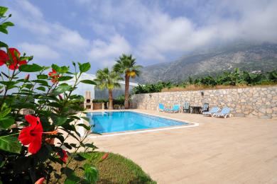 Proprietate în Alanya cu balcon mobilat cu mobilier din ratan, balustradă din fier forjat și vederi pitorești la munte.