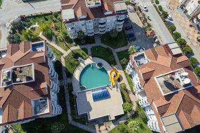 Der helle, geschlossene Alanya-Balkon verfügt über eine Essecke, einen Fliesenboden und raumhohe Fenster mit Plissees.