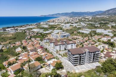 Alanya eign stofa með mjúkum flauelssófum, mynstruðu veggfóðri og björtu, loftgóðu andrúmslofti.