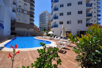 Lichte Alanya appartement keuken met moderne witte kasten, donkere werkbladen, marmeren vloeren en veel natuurlijk licht.