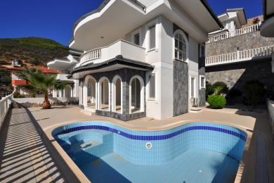 Balcon de propriété à Alanya avec des sols en marbre, une balustrade blanche et une vue imprenable sur la mer sous un soleil éclatant.