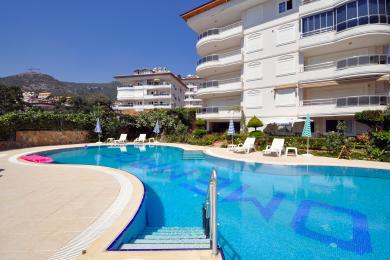 Alanya woning balkon met smeedijzeren meubilair, heldere zon en panoramisch uitzicht op de stad.