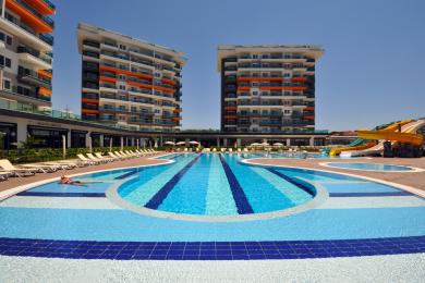 Alanya property balcony with glass railings offers bright views of the pool and nearby buildings.