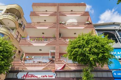 Balcone di proprietà ad Alanya con set da pranzo in vimini, pavimento in piastrelle e vista panoramica sulla città e sulle montagne.