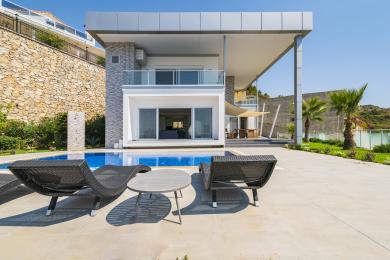 Vanjski izgled vile u Alanji s privatnim bazenom, modernim dizajnom, kamenim zidom i sunčanom, luksuznom atmosferom.