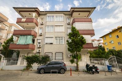Svijetli apartman u Alanji ima kuhinju otvorenog plana s bijelim ormarićima, podovima od pločica i udoban dnevni boravak.