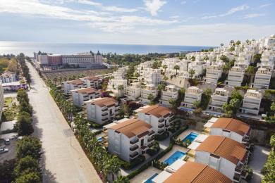 Alanya mulki: Zamonaviy oshxonasi, bej divani va jilolangan kafel pollari bo'lgan yorug', ochiq rejadagi yashash xonasi.