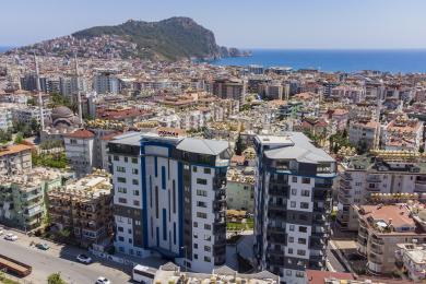 Un balcone luminoso ad Alanya con ringhiere in vetro offre viste mozzafiato sulla città e sul mare attraverso grandi porte scorrevoli in vetro.