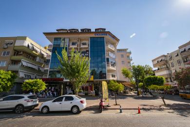 Σαλόνι ακινήτου στην Αλάνια με μπεζ καναπέ, πλακάκια, πρόσβαση σε μπαλκόνι και μοντέρνο φωτισμό.