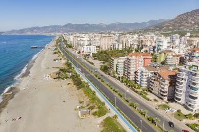 Balcón de propiedad en Alanya con vista al mar, con juego de comedor al aire libre y barandilla decorativa de hierro forjado a plena luz del sol.