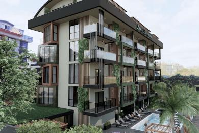 Alanya Immobilie Wohnzimmer mit moderner Küche, mit einem grauen Sofa, einem grünen Ottomanen und warmer, einladender Beleuchtung.