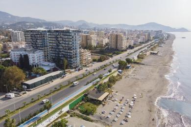 Alanya nehnuteľnosť, obývacia izba s moderným nábytkom, neutrálnymi tónmi, dlažbou a jasným zapusteným osvetlením.