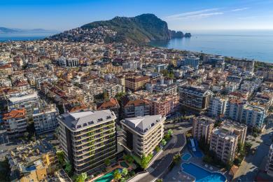 Alanya'da mermer detaylara, modern mutfağa ve parlak, sofistike bir atmosfer yaratan zarif avizeye sahip daire oturma odası.