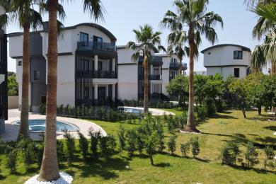 Ljust vardagsrum i Alanya med marmorgolv, böjda fönster och modern belysning, vilket skapar en rymlig atmosfär.