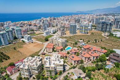 Alanya ejendom altan med kurvemøbler, glasbord og udsigt over byen under klart, naturligt lys.