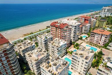 Balkon nekretnine u Alanji sa nameštajem od ratana, staklenim stolom i svetlim, sunčanim pogledom na more.