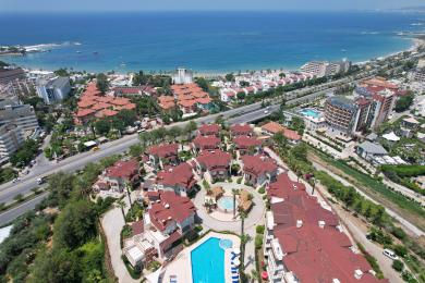 Svetla, otvorena dnevna soba apartmana u Alanji sadrži modernu kuhinju, trpezarijski set i udobno sedenje pod toplim osvetljenjem.