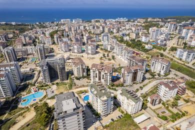 شرفة مشمسة في ألانيا تطل على المسبح، وتتميز بمجموعة لتناول الطعام وأجواء مشرقة ومتجددة الهواء.
