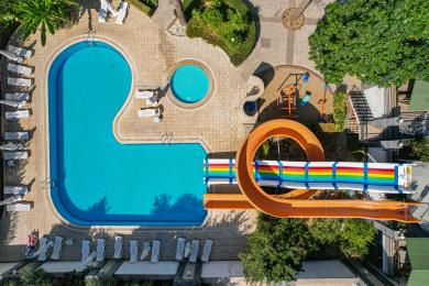 Alanya shahridagi balkon, to‘qilgan mebellar va shisha stol bilan yorug‘ kunduzda ajoyib shahar va dengiz manzaralarini taqdim etadi.