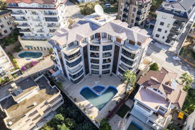 Proprietate în Alanya: Balcon închis cu pereți de sticlă, mobilier din răchită și atmosferă luminoasă și aerisită, cu vedere la oraș.