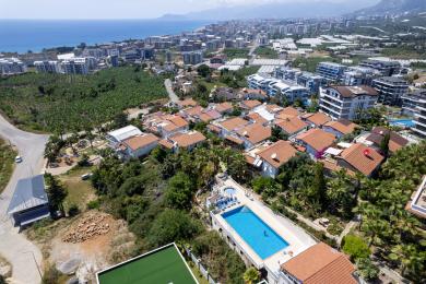 Балкон на имот во Аланија со дрвен покрив, бел мебел и прекрасен поглед на море, создавајќи релаксирачка атмосфера.