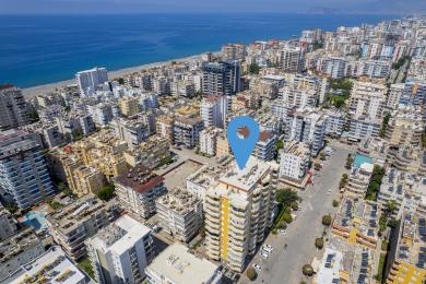 Luftaufnahme einer Immobilie in Alanya, die die Lage des Gebäudes in der Nähe des Strandes und des Stadtzentrums zeigt.