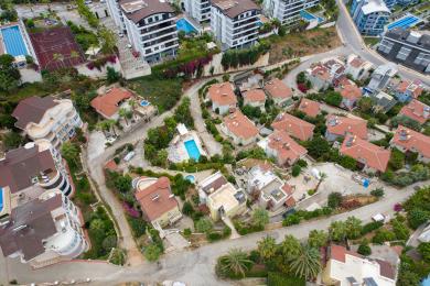 Alanya ingatlan erkélye fonott bútorokkal, ragyogó nappali fénnyel és lenyűgöző tengerparti kilátással, pihentető légkört teremtve.