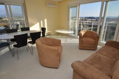 Lichte Alanya woonkamer met tegelvloeren, suède meubels, eettafel en panoramisch uitzicht over de stad.
