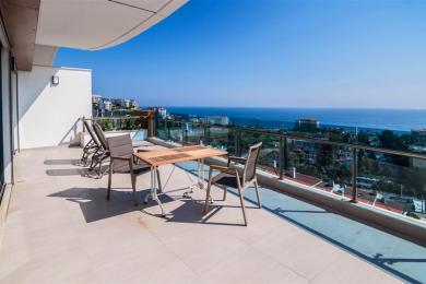 Alanya property balcony with tile flooring, glass railings, and outdoor furniture overlooking the Mediterranean Sea.