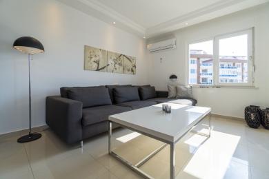 Bright, modern apartment living room featuring a comfortable sectional sofa and sunlit window views.