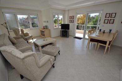 Alanyada parlaq, kafel döşəməli, rahat oturma yerləri və balkona çıxışı olan qonaq otağı, rahat bir atmosfer yaradır.