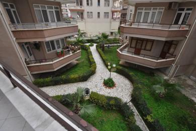 Alanya mulkining tosh yo'laklari va kvartira balkonlari bo'lgan obodonlashtirilgan hovlisi ko'rinishi.