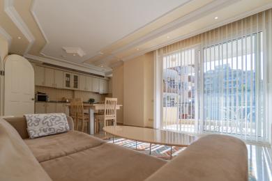 Alanya lejlighed stue med åbent køkken, lyst lys, adgang til balkon og neutrale, komfortable møbler.